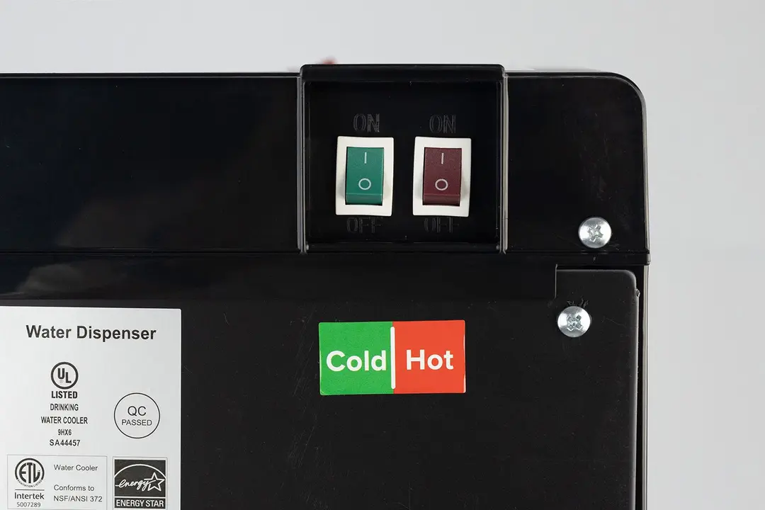 Close up of two switches at the rear of a water cooler dispenser - green for the cold water tank and red for the hot.