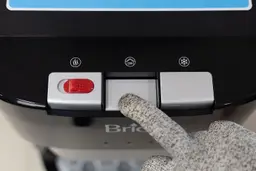 A hand holding down the middle button on a water cooler dispenser to demonstrate the space between the buttons.