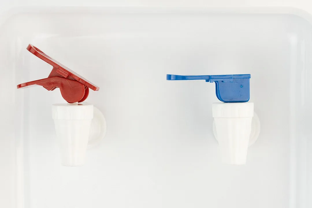 A close up to two lever type dispensing faucets on a water cooler dispenser.