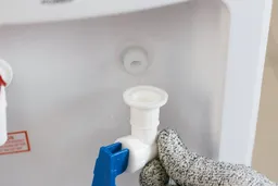 A cold water faucet which has been unscrewed from its connection to a water cooler dispenser.