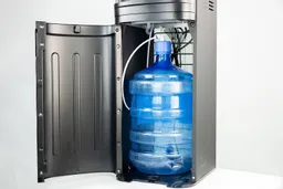 A bottle with a water straw inserted inside the cabinet of a bottom-loading water cooler dispenser.