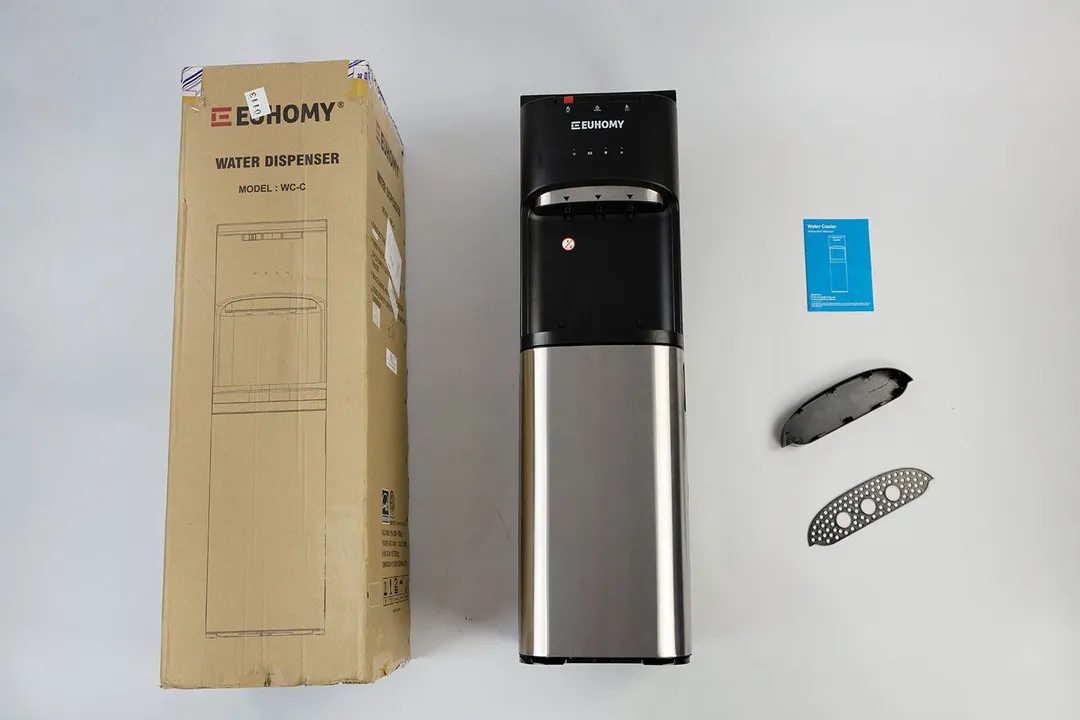 The unboxed Euhomy water cooler dispenser besides its box to the left and the drip tray and user manual to the right.