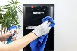 Close up showing a gloved hand with a cloth cleaning the display panel of Euhomy water cooler dispenser.