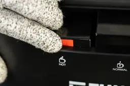 Close up of how to operate the hot water safety button on a water cooler dispenser.