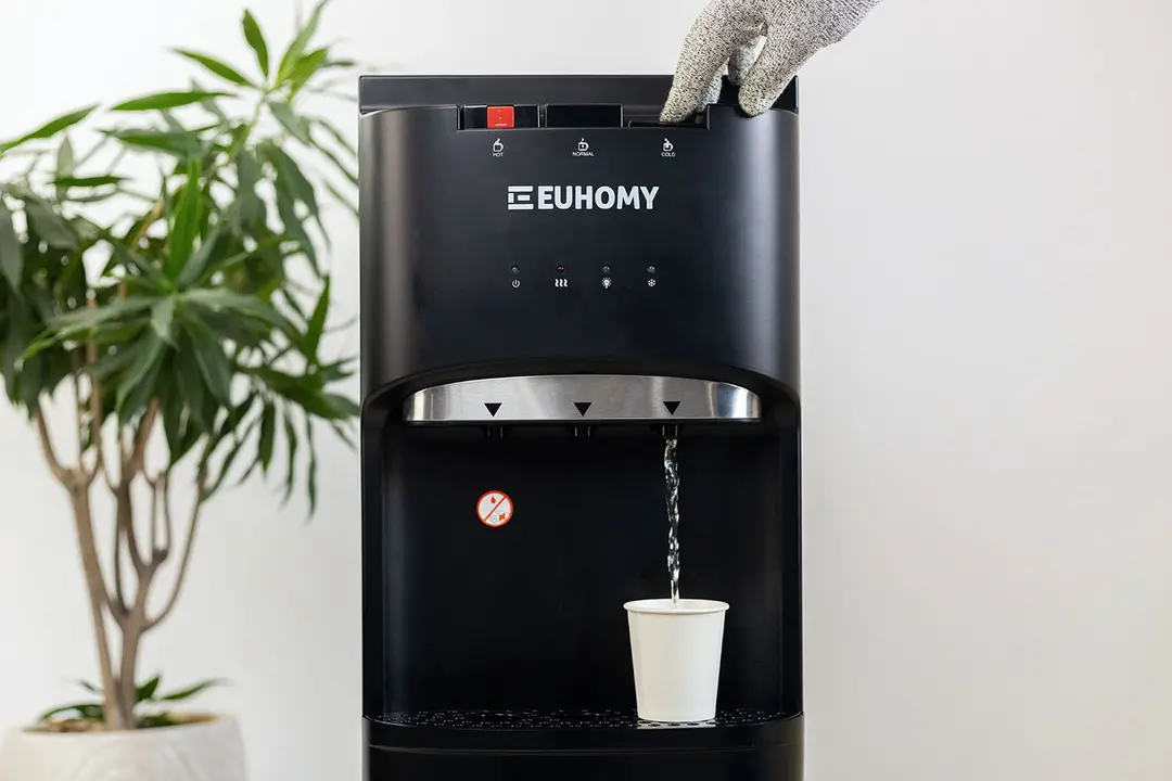 Dispensing cold water into a paper cup resting on the drip tray of the Euhomy bottom-loading water cooler dispenser.