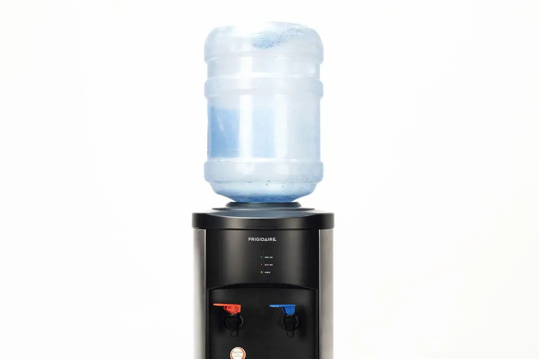 A water bottle set in place on a top loading water cooler dispenser.