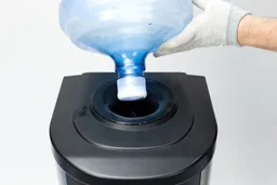 A demonstration on how to set up a bottle onto a top loading water cooler dispenser.