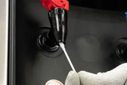Cleaning the inside of a water faucet of a water cooler dispenser with a cotton Q-tip.