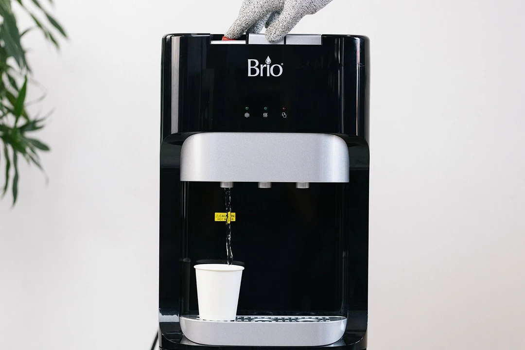 Hot water being dispensed from a button-operated bottom-loading water cooler dispenser.