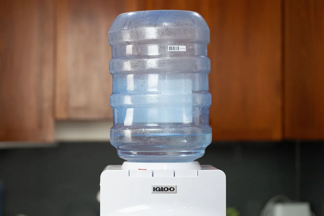 A water bottle loaded onto the Igloo hot and cold water cooler dispenser.