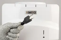 A gloved hand showing the plug of the Igloo water cooler dispenser against the front panel background.