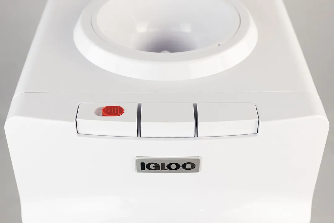 A close up top down view of three white buttons of a water cooler dispenser.