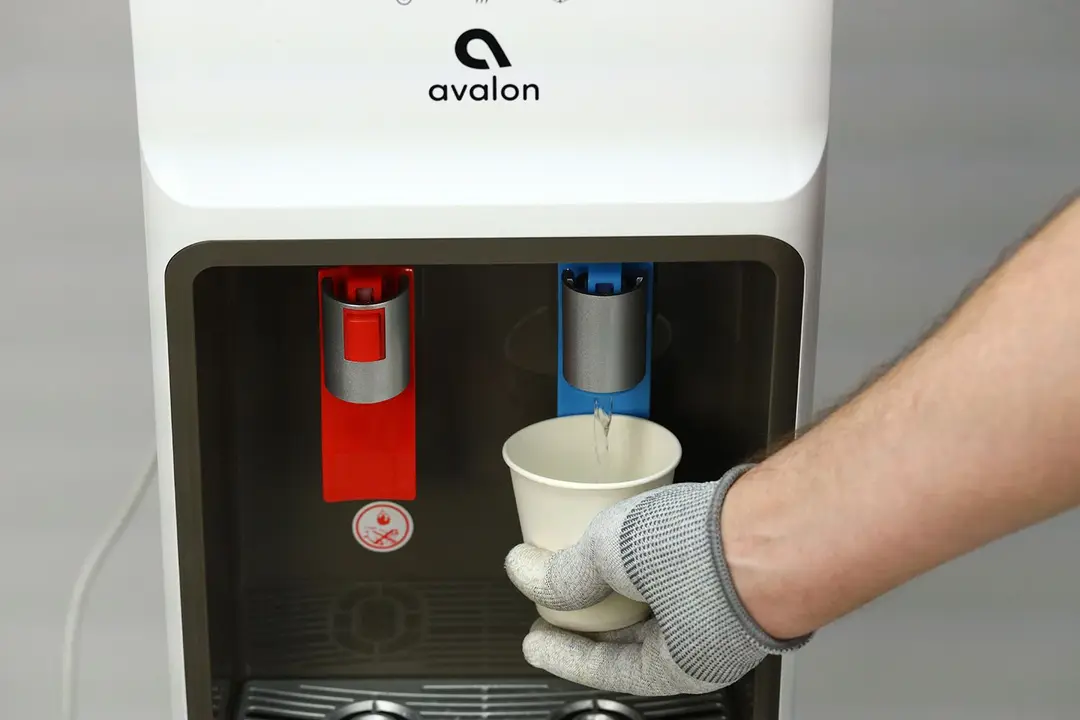 Water being dispensed from a water cooler dispenser with a touchless lever.