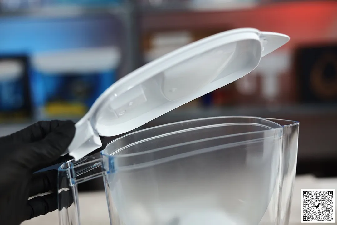 The top part of the Brita Aluna, a gloved hand holding and opening the lid