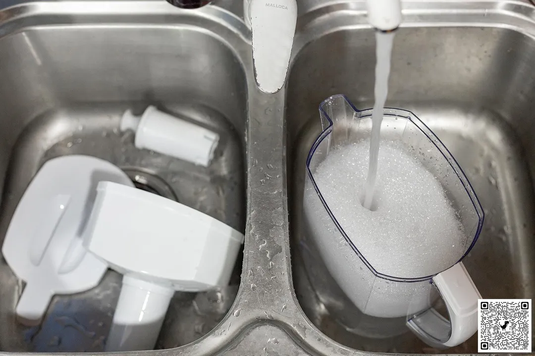 parts of the Brita Everyday water filter pitcher in a duo-sink, with water running and foam in the pitcher