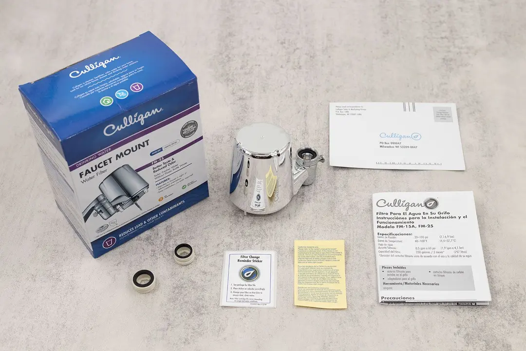 The glossy housing of the Culligan FM-25 faucet-mount water filter next to its shipping box, adapters, and paperwork.