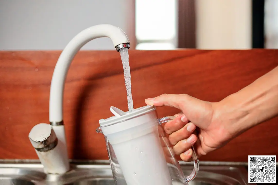 Hand holding the LifeStraw pitcher to refill under running faucet