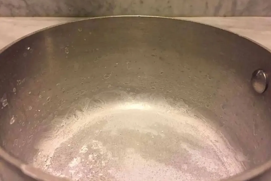 Milky hard water residue at the bottom of a pot after boiling