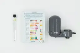 The test strips on a color chart in the center. To the right is the PUR Plus FM2500V filter. Left is a vial of water.