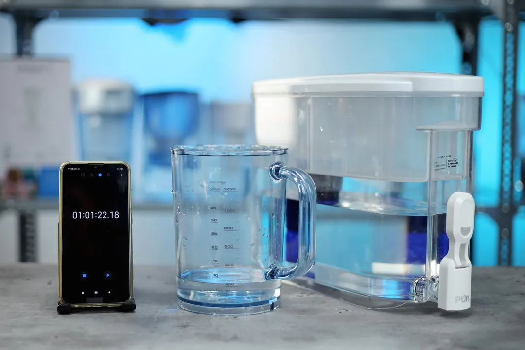The PUR plus 30 cup water filter dispenser, a water container, and a smartphone timer