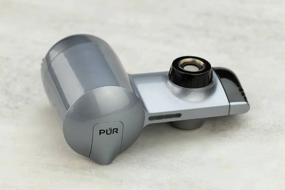 The front of the grey, plastic PUR Plus PFM350V filter, which is sitting on a white stone table.