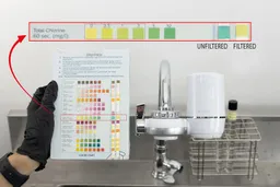 The color chart with two used test strips stuck to it is held to the right of the Waterdrop WD-FC-01.