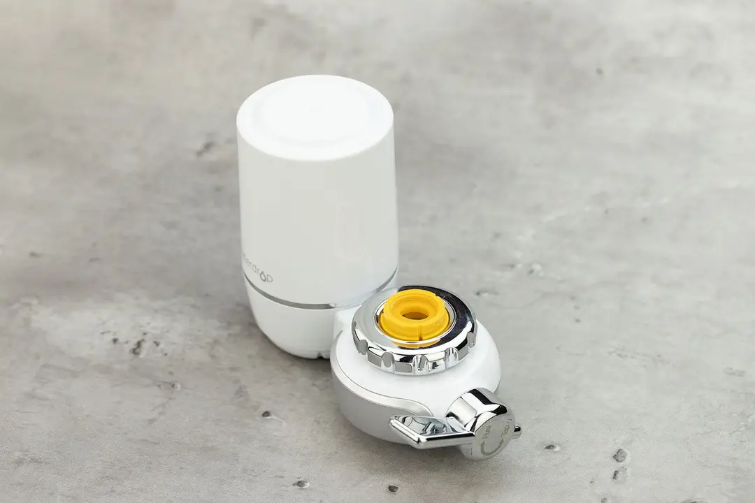 The Waterdrop WD-FC-01 with a yellow faucet adapter attached to its mounting port through the silver plastic twist ring.