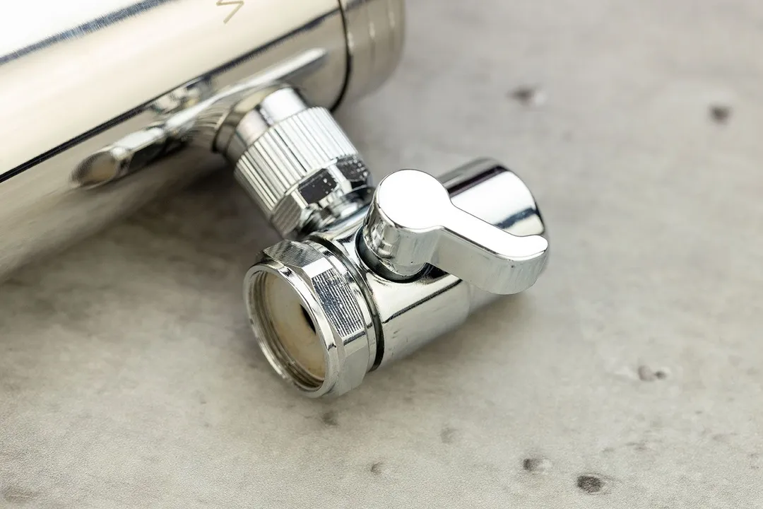 The silvery, chrome-plated rotating handle of the routing valve on the side of the Waterdrop WD-FC-06 faucet-mount filter.