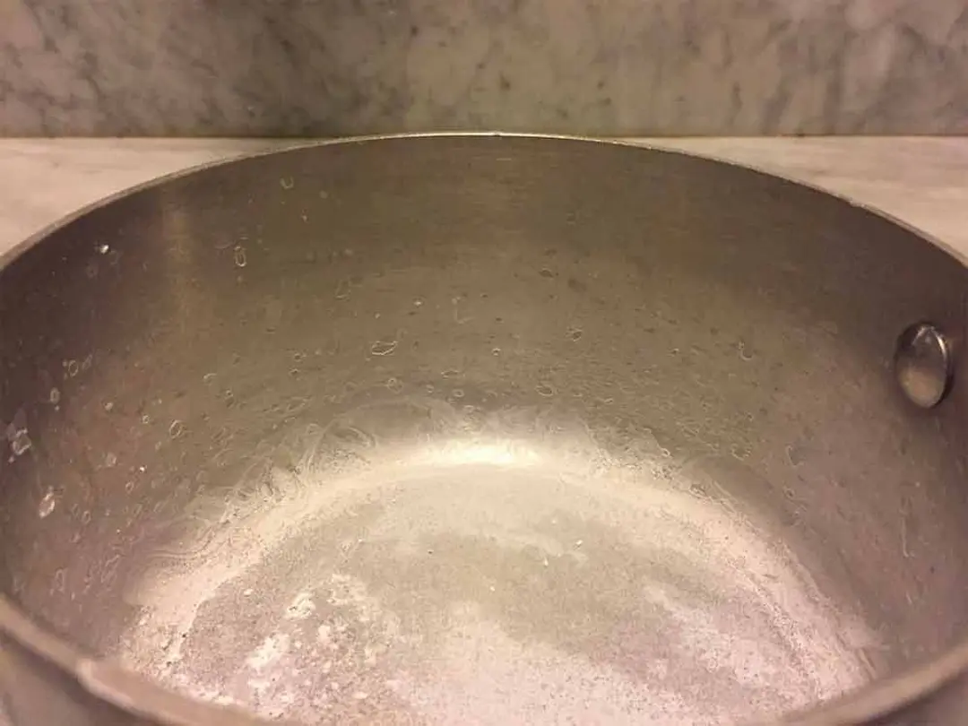 Milky hard water residue at the bottom of a pot after boiling